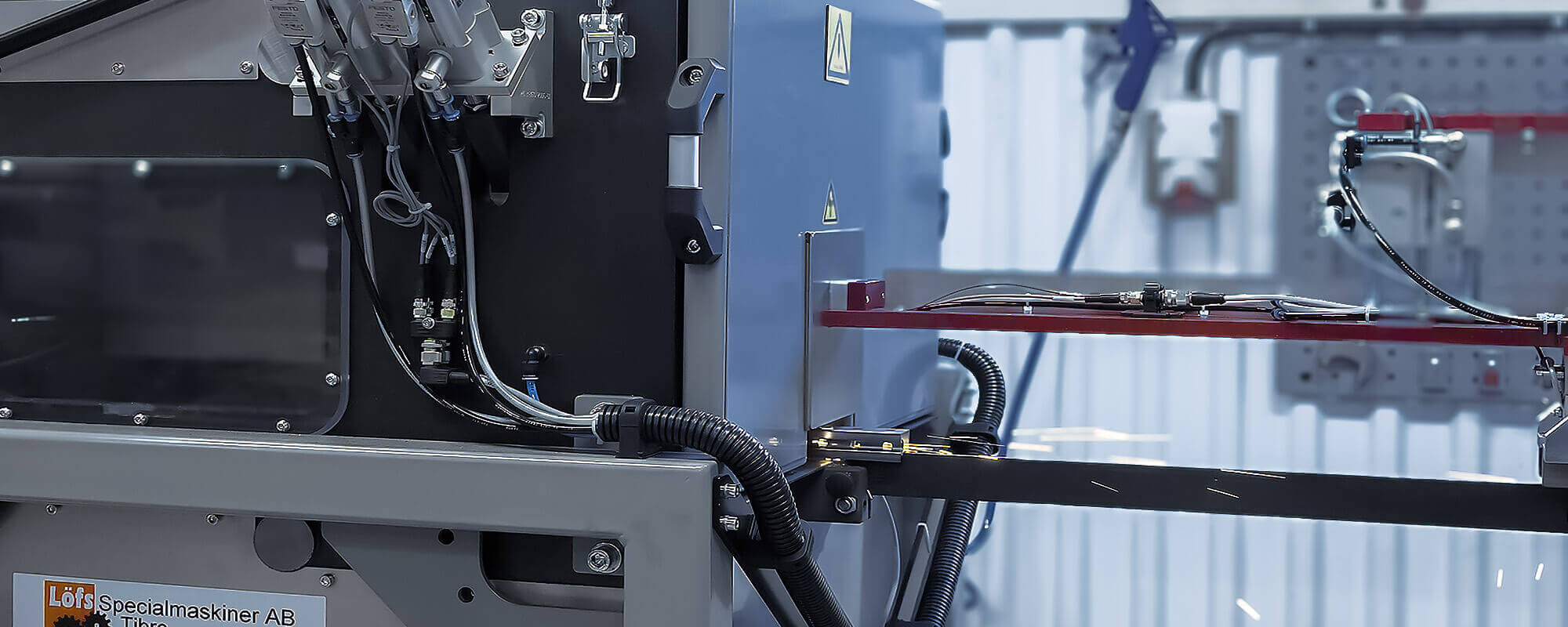 Close-up of complex industrial machinery with wires, tubes, and metal components in a factory.